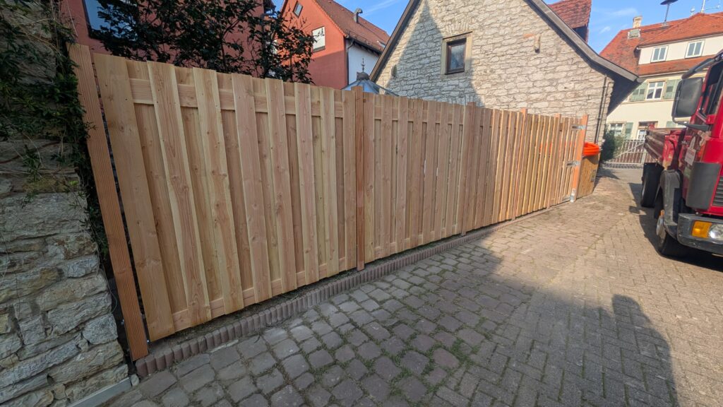 Neuer Holzzaun an Kopfsteinpflaster.