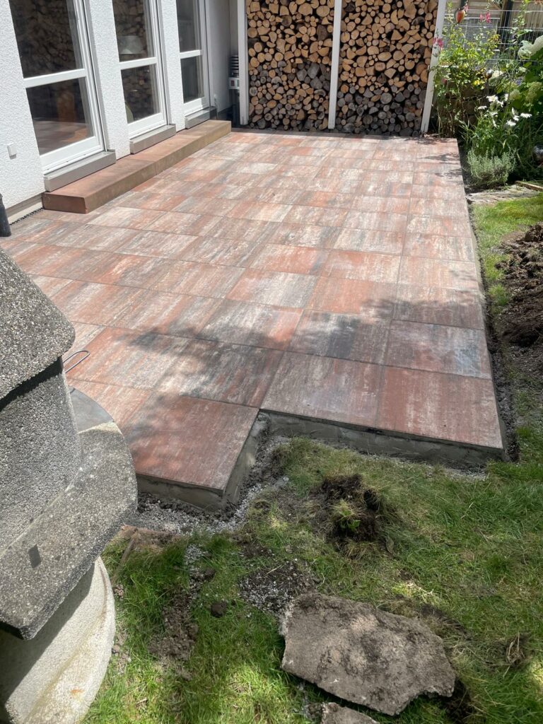 Frisch verlegte Terrasse, Holzstapel daneben.